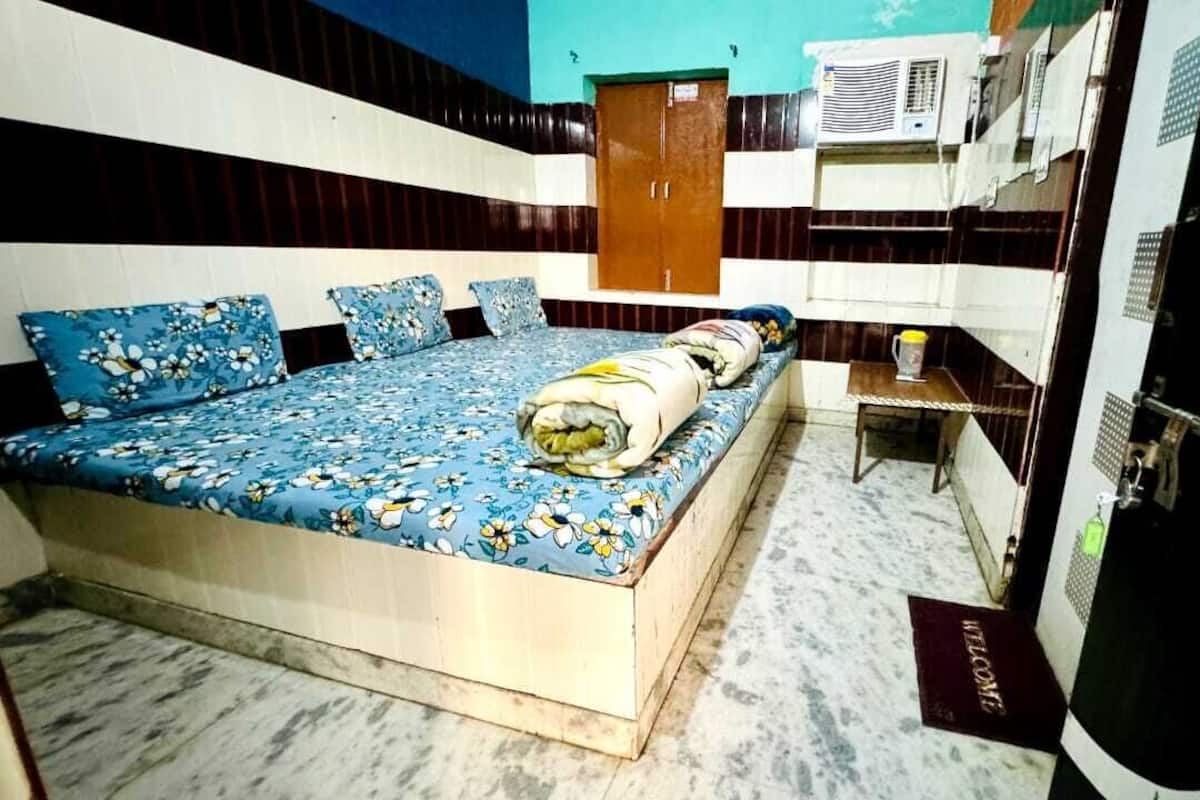 Ein Zimmer mit einem Bett, einem Holzschrank, einem kleinen Tisch und einer Wand-Klimaanlage.
