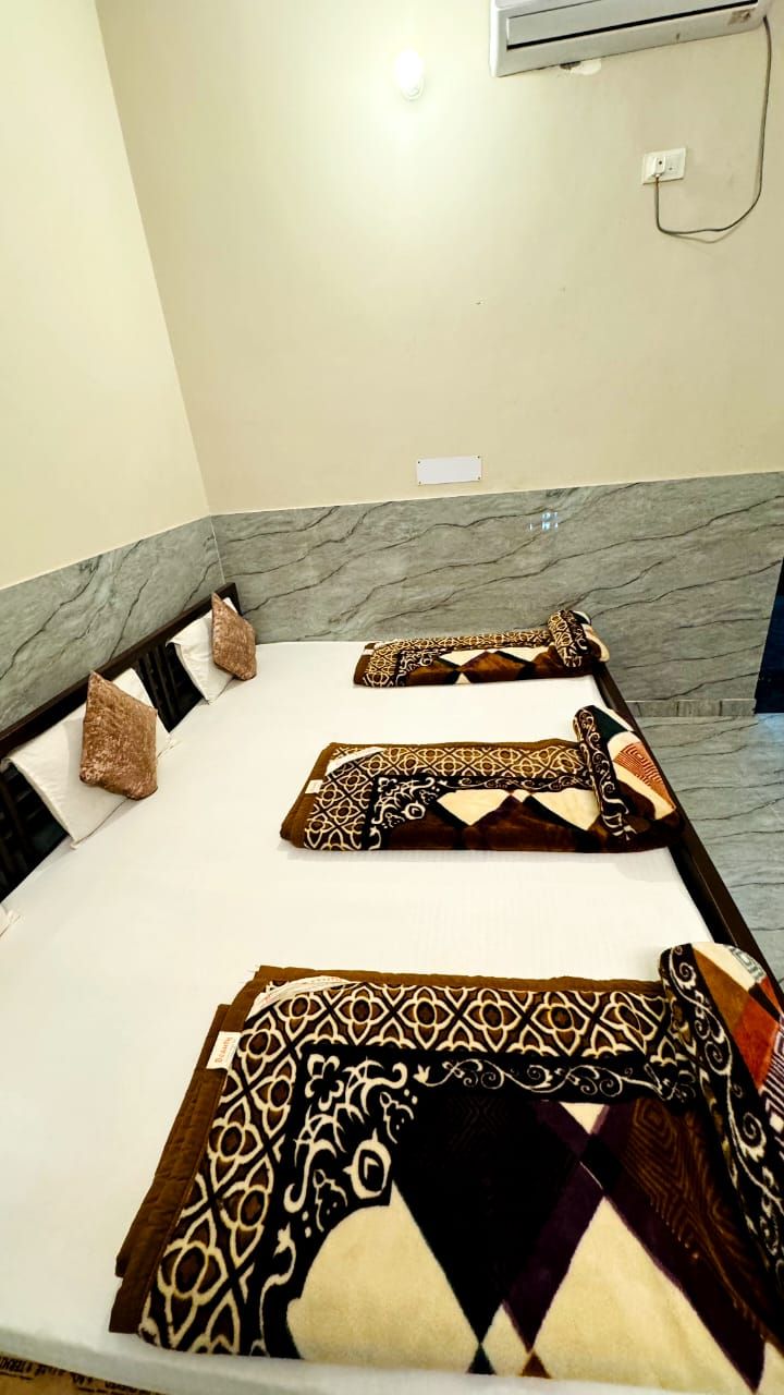 A hotel room with a bed, a marble wall, and an air conditioning unit.