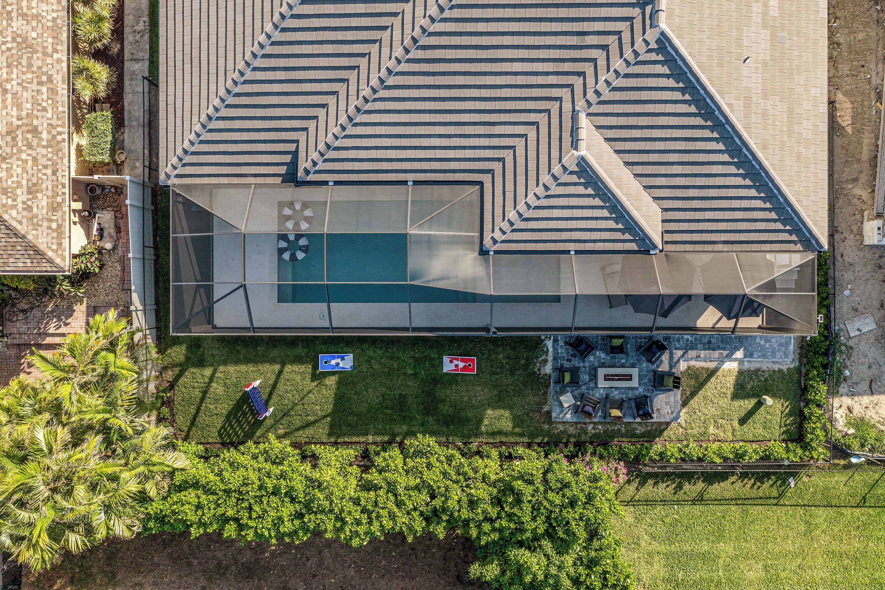 An aerial view of a modern building with a unique geometric roof design, a swimming pool, and a landscaped area with a wheelchair-accessible path.