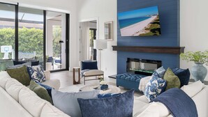 A modern living room with a sofa, coffee table, and a fireplace. - Luxury 5BR - Pool, Game Room, Mini Golf, Fire Pit (Marco Island)