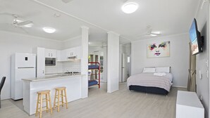 Un appartement moderne et compact, doté d’une kitchenette, d’un lit, d’une télévision et d’un petit coin salon.