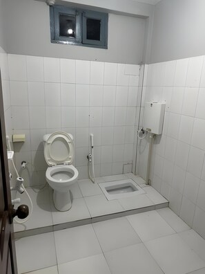 A compact bathroom with a toilet, bidet, and shower area.