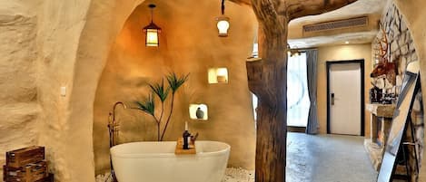 Une salle de bain rustique avec une grande baignoire, des poutres en bois et des murs en pierre.