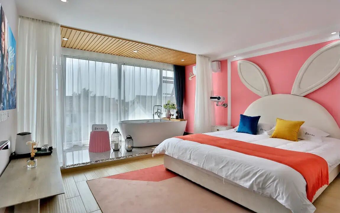 A modern bedroom with a large bed, a bathtub, and a city view.
