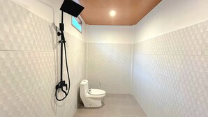 A small, modern bathroom with a toilet, a shower, and a ceiling light. - NeNa Eat and Sleep Kuta (Kuta)