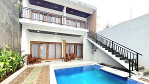 A two-story building with a swimming pool, a staircase, and outdoor seating. - NeNa Eat and Sleep Kuta (Kuta)