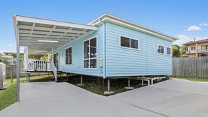 A light blue house with a covered patio area, a fenced yard, and a clear sky. - HONU, part of the Ohana Surf Bungalows (<5 minute walk to beach and shops). (Scotts Head)