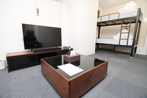 Una habitación moderna con televisor de pantalla plana, una mesa de centro de madera, una cama litera y suelo alfombrado.