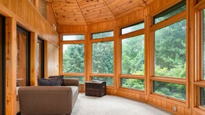 Ein geräumiger Raum mit großen Fenstern, einem braunen Sofa und einer kleinen Holzkiste.