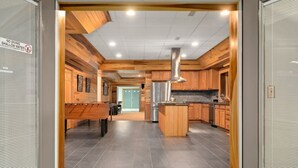 Eine moderne Küche mit Holzschränken, einer zentralen Kochinsel und einem Edelstahl-Kühlschrank.