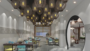 Un restaurante con una larga mesa dispuesta para comer, un techo decorativo y una vista a través de un arco.