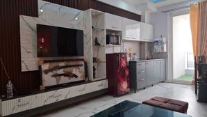Ein modernes Wohnzimmer mit großem Fernseher, Kamin und Glastisch.