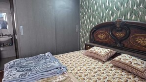 Ein Schlafzimmer mit einem Bett, Kissen, einer Decke, einem Holzkopfstück und einem Spiegel.