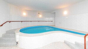 A swimming pool with a curved edge, surrounded by a tiled deck and a staircase with a wooden handrail. - Victoria Hotel (Gori)