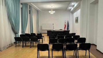 Une salle de conférence équipée d’un tableau blanc, d’une table avec des chaises et de drapeaux accrochés au mur.
