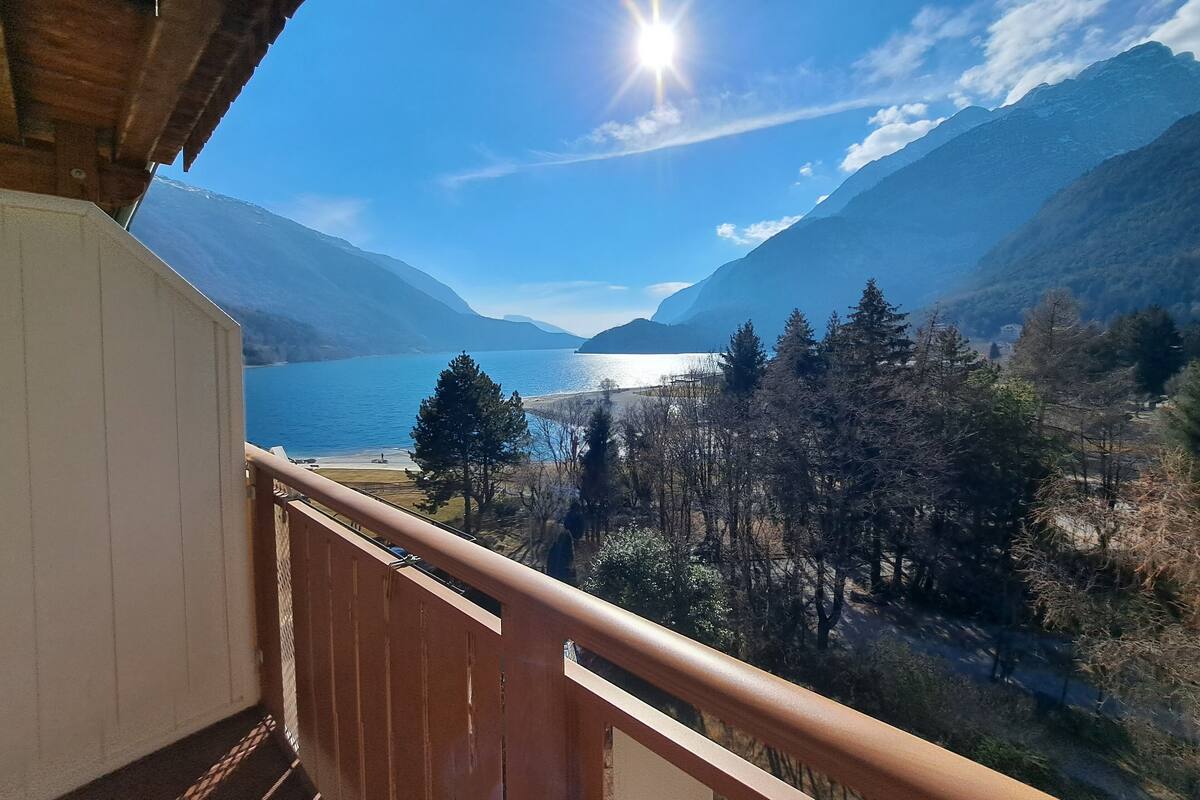 Un balcón con vista a un lago, montañas y un cielo despejado.