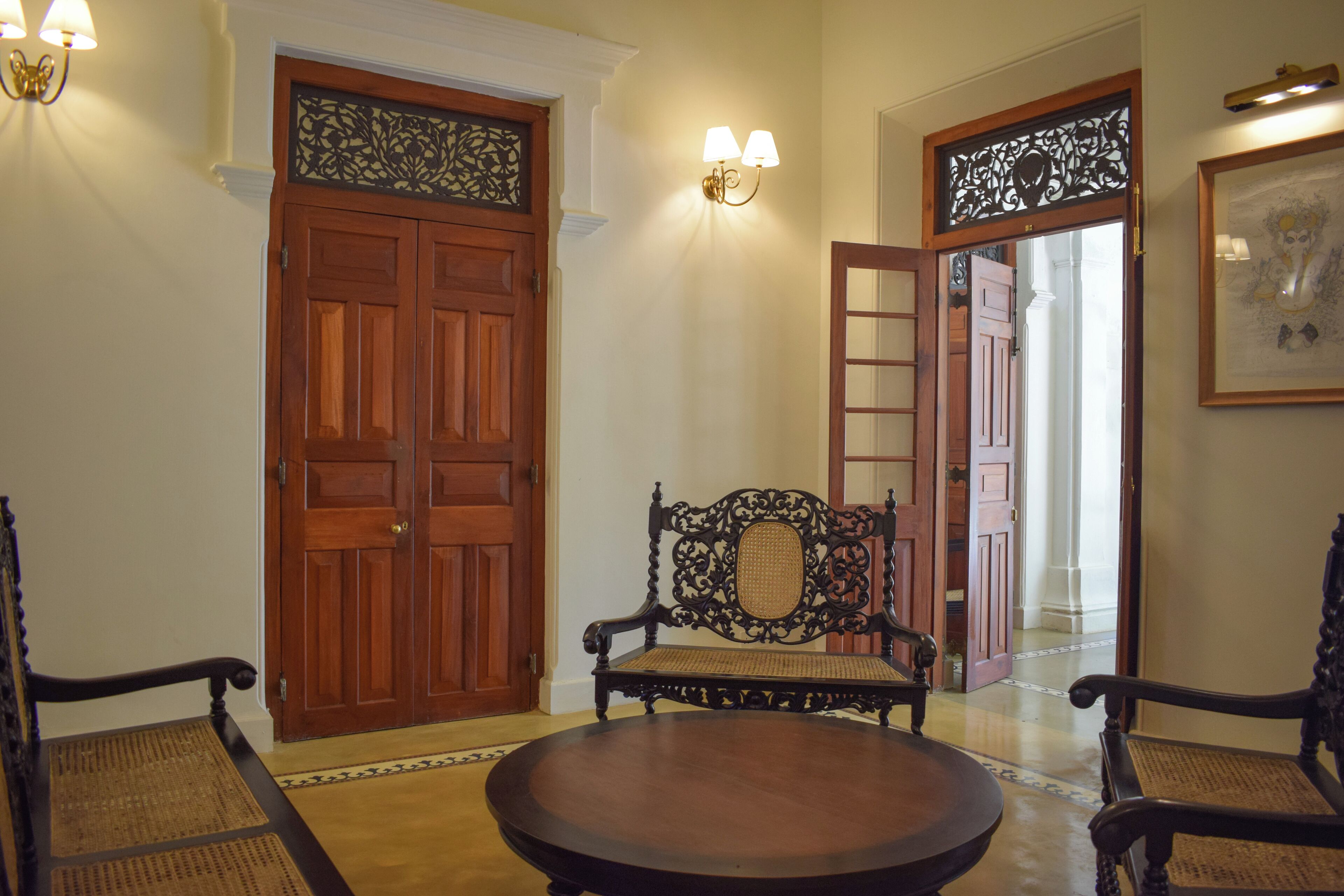 A room with a wooden door, a bench, and a round table.