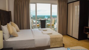 Camera d'albergo con un letto grande, una scrivania con sedia e vista sulla città.