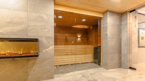 Een moderne lobby met een glazen haard, houten lambrisering en een marmeren vloer.