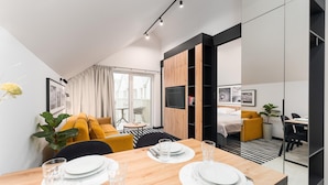 Een moderne hotelkamer met een zithoek, een bank, een televisie en een bed.