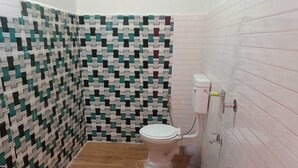 Un baño con pared estampada, un inodoro, un cubo verde y un cubo rosa.