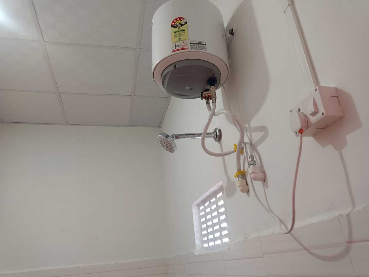 A bathroom with a white tiled floor, a white shower enclosure, and a water heater mounted on the wall.