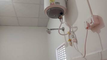 A bathroom with a white tiled floor, a white shower enclosure, and a water heater mounted on the wall.