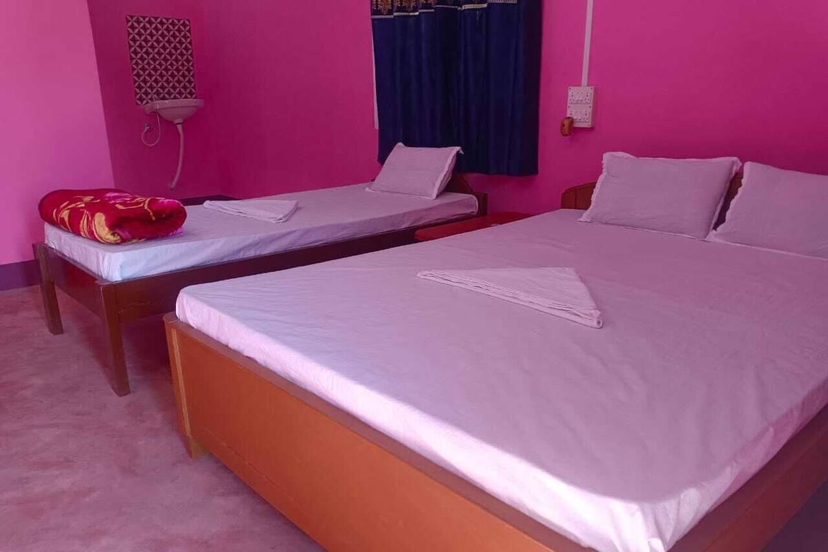 A room with two beds, a bedside table, a wall-mounted heater, and a power outlet.