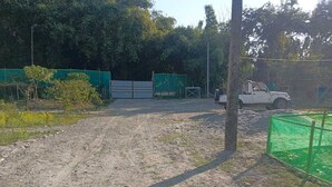 Un sendero de tierra que lleva a un área cerrada con un vehículo blanco estacionado cerca.