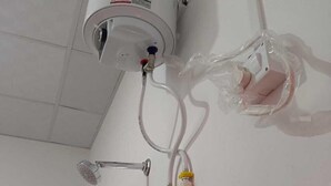Un baño con ducha, techo blanco y ventana con diseño de celosía.