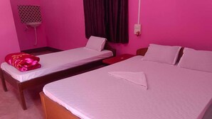 Una habitación con dos camas individuales y una cama más grande, todo con ropa blanca.