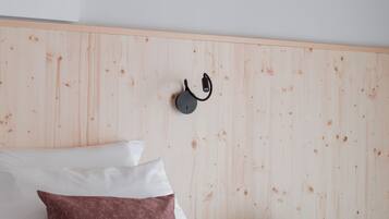 A bedroom with a wooden headboard, a bed with white and brown bedding, a nightstand with a book, and a wall-mounted lamp.