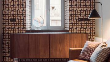 Una sala de estar moderna con un mueble de madera, una mesa redonda con libros y una lámpara, un sofá de cuero con cojines estampados y una ventana decorada con un globo terráqueo.