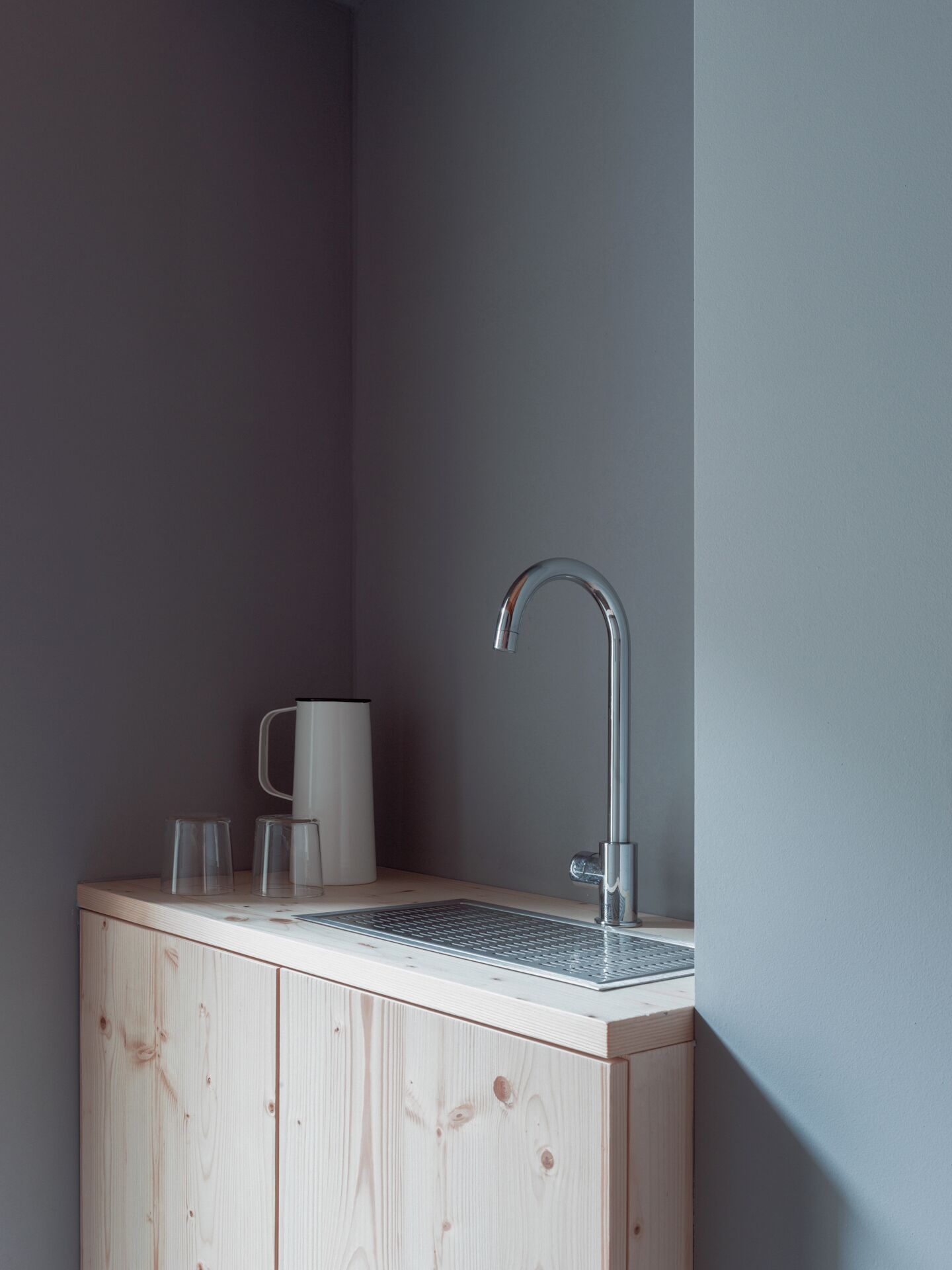 A small, modern kitchen with a wooden countertop, a stainless steel sink, and a coffee maker.
