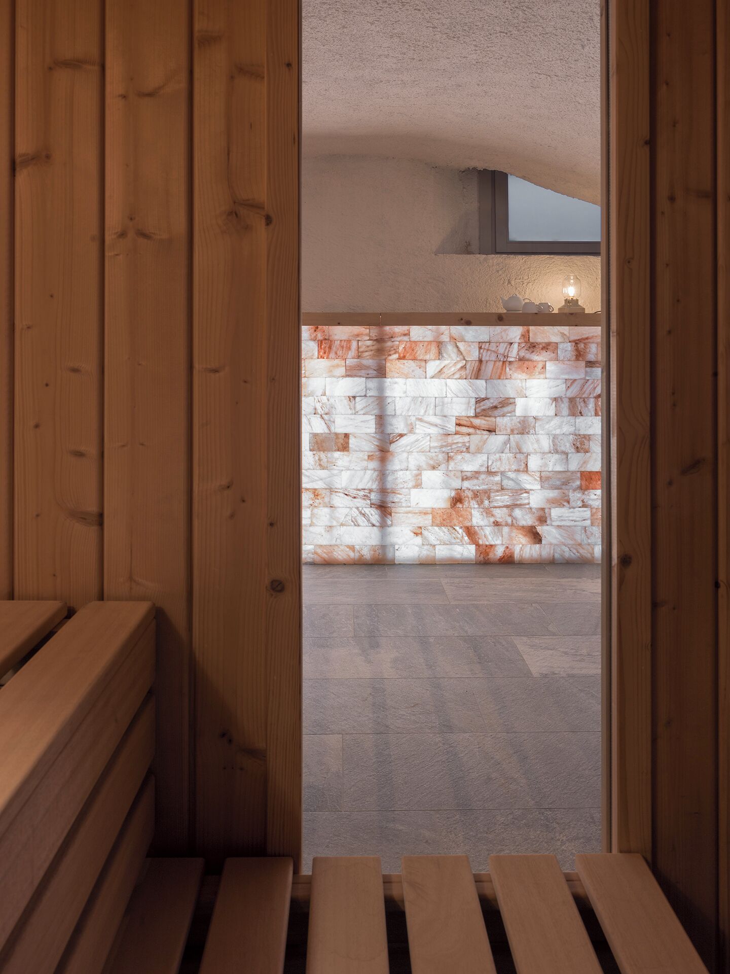 A wooden bench area leading to a stone wall with a view of the sky.