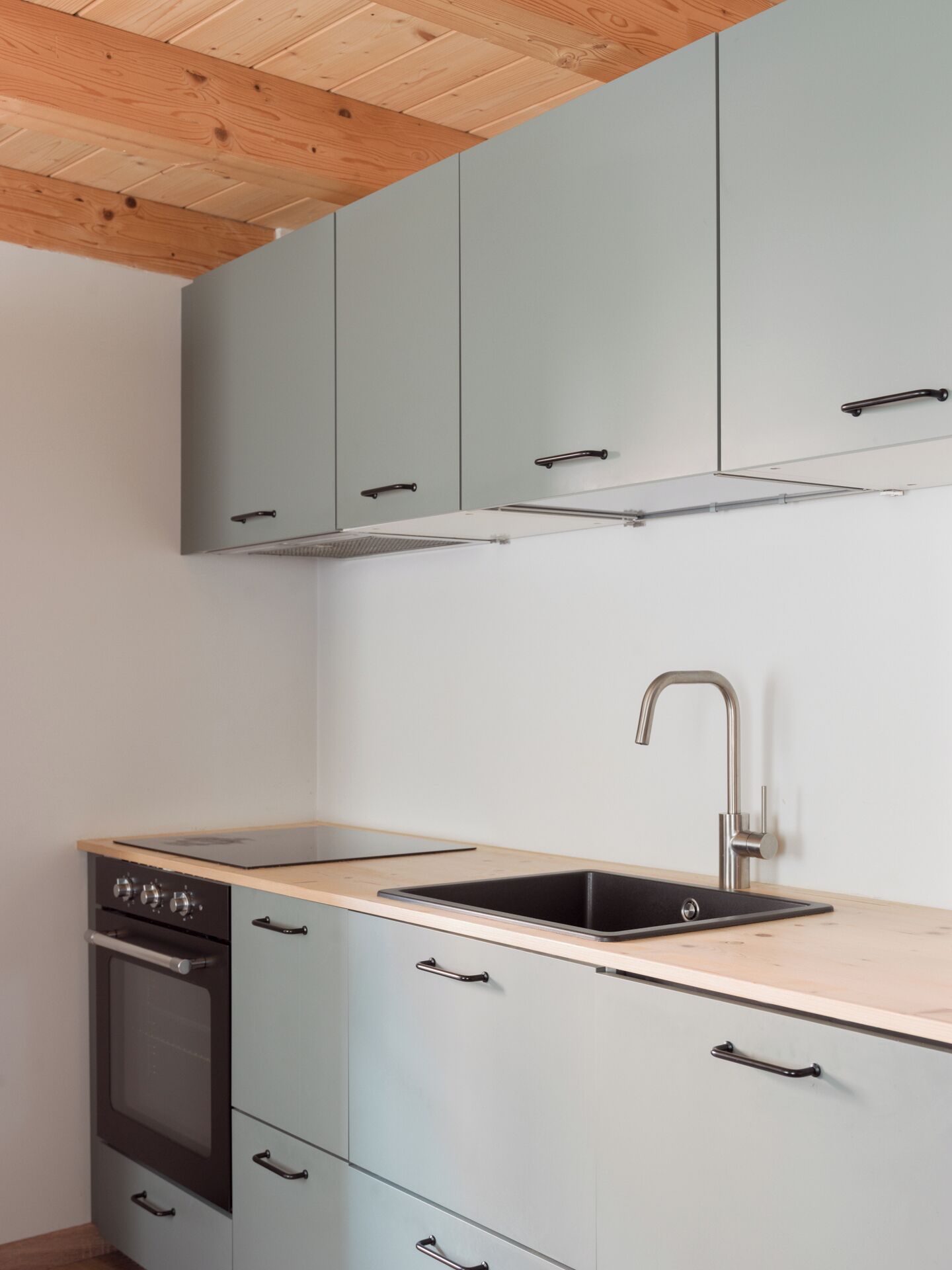 Una cocina compacta con armarios azul claro, un lavamanos de acero inoxidable y un horno empotrado.