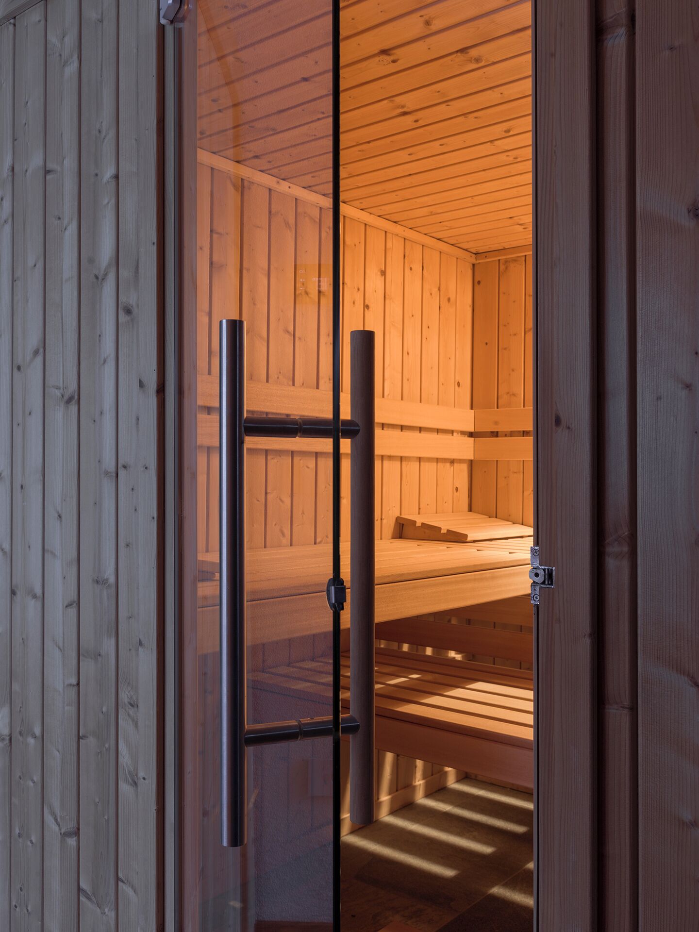 Un sauna de madera con un banco y una puerta de vidrio.