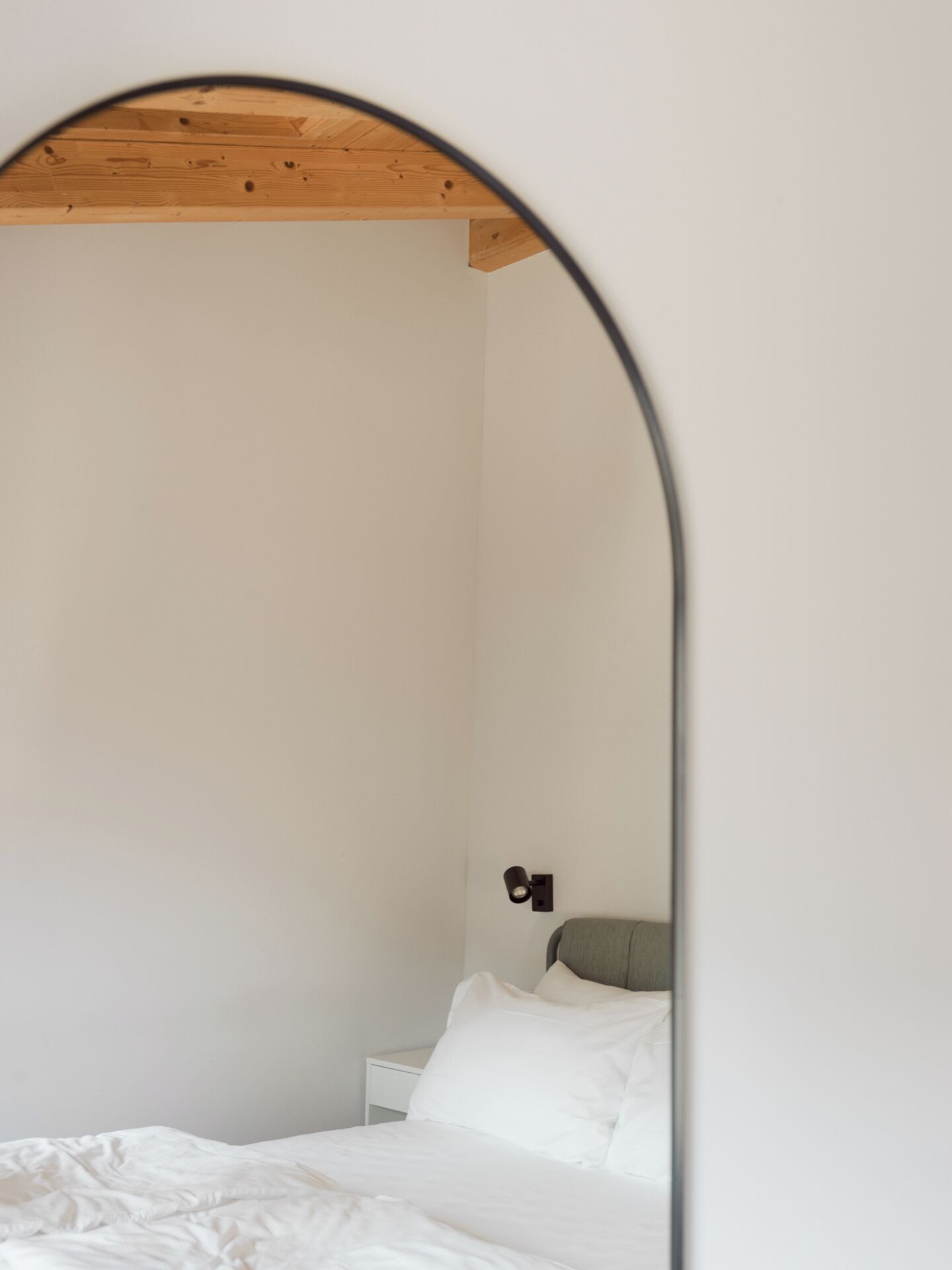 Une chambre à coucher avec un plafond en bois, un lit blanc et une table de chevet avec une lampe.