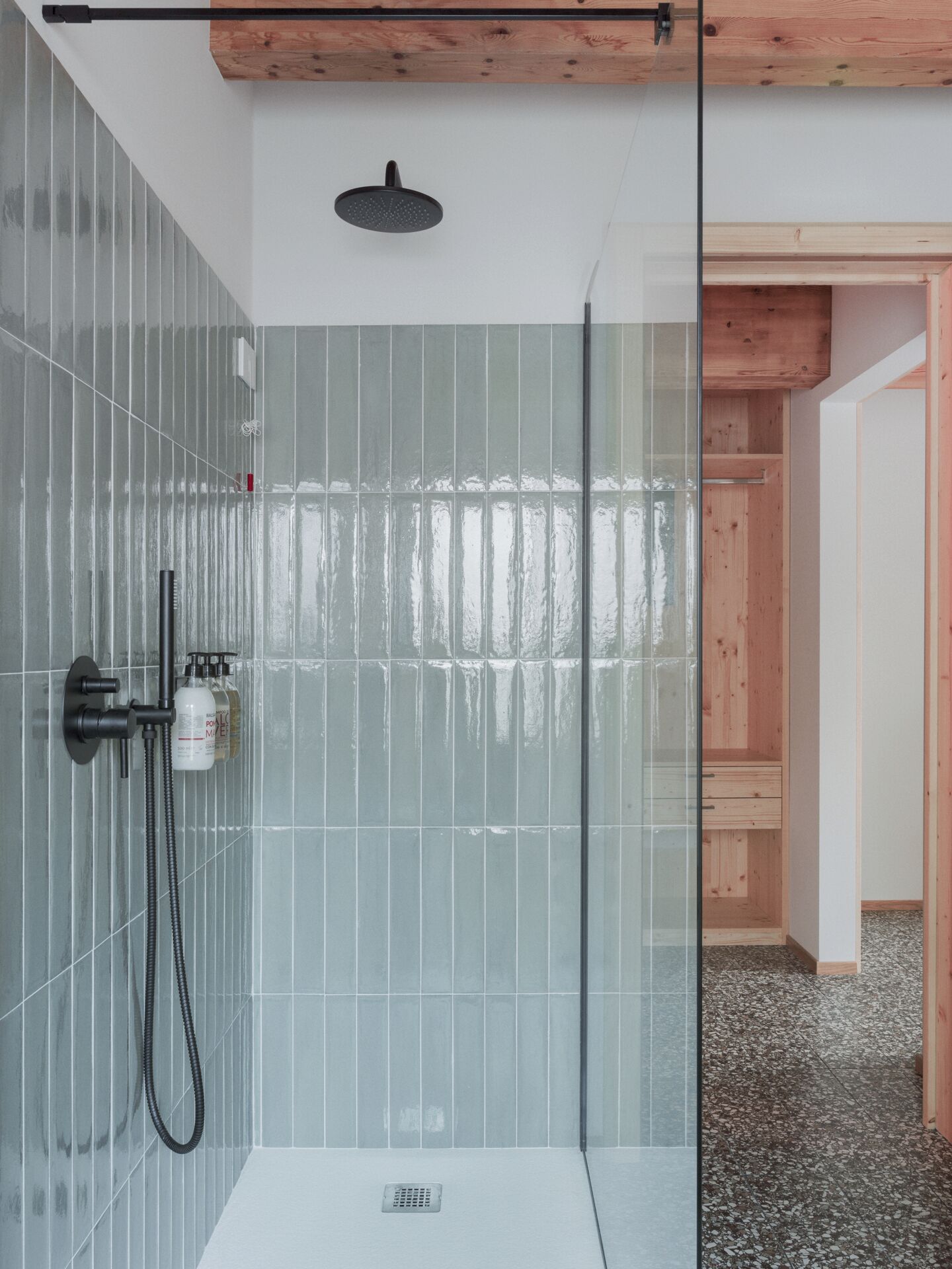 Een moderne douche met glazen deur, handdouche en extra douchestraal.