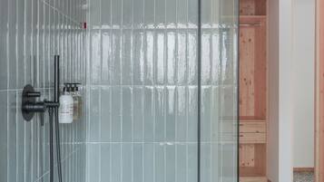 Een moderne douche met glazen deur, handdouche en extra douchestraal.