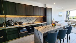 A modern kitchen with dark cabinetry, a marble countertop, and a built-in island with bar stools. - Penthouse perfection with private rooftop pool paradise. 2 bed, 2 bath, parking (Waterloo)