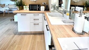 A modern kitchen with white cabinetry, a wooden countertop, and a large mirror above the sink. - Saint-Raphaël - Apartment near Valescure golf course and sea.  (Saint-Raphaël)