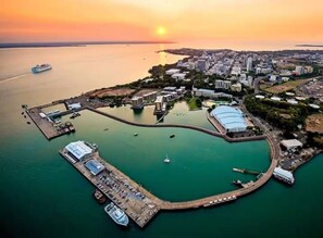 An aerial view of a coastal city with a marina, buildings, and a sunset. - Zen By The Sea Pool - Balcony Dining - Seaview (Darwin)