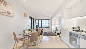 Eine moderne Küche mit Essbereich, ein großes Fenster mit Aussicht und eine kleine Wohnarea mit einer Couch.