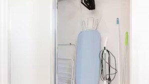 A neatly organized closet with a hanging rack, ironing board, and cleaning supplies. - Smart Suites Self Check-in Apartments - 35 Freney (Rocklea)