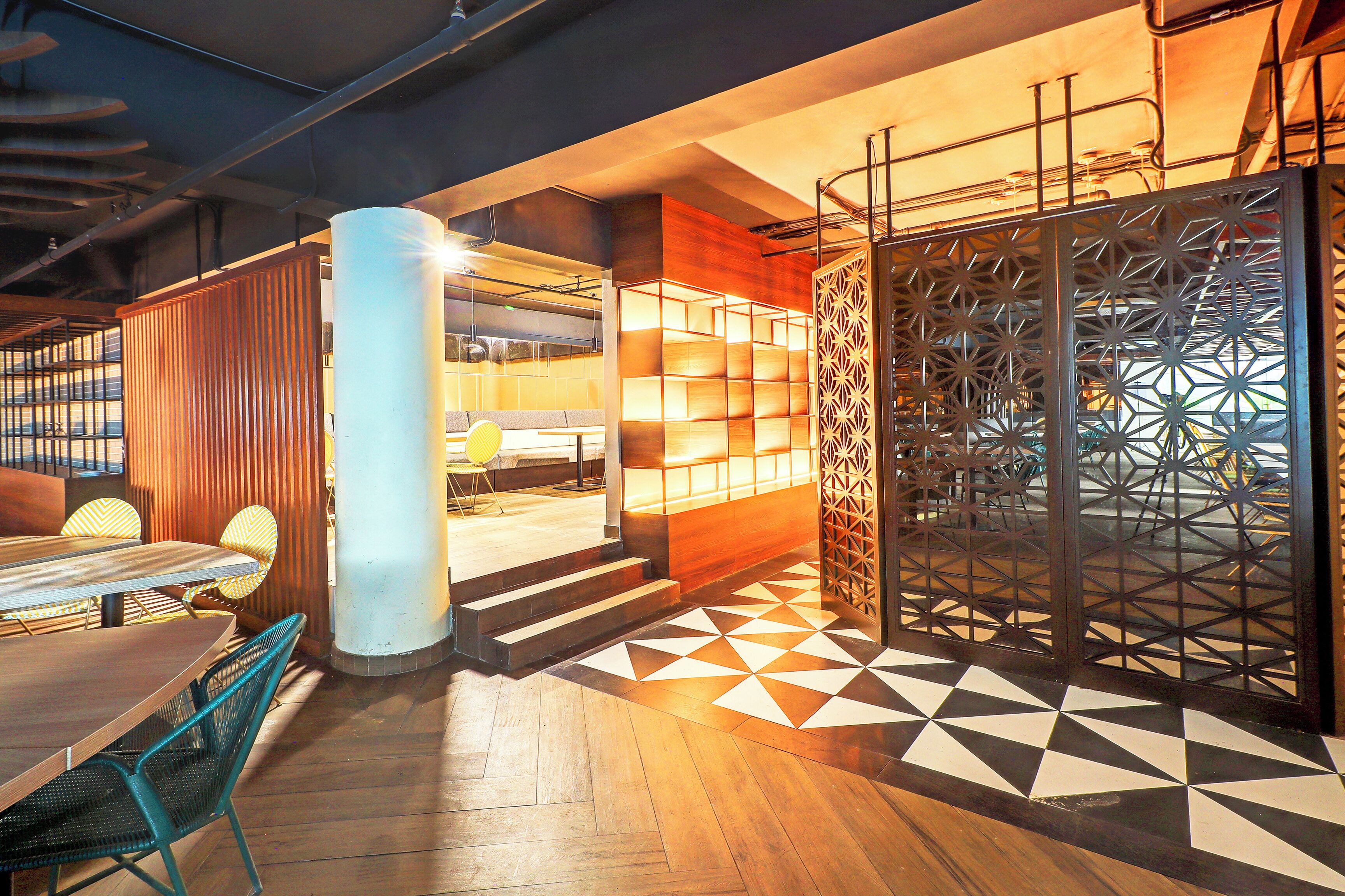 A modern interior with a wooden floor, a seating area with a table and chairs, and a patterned wall.