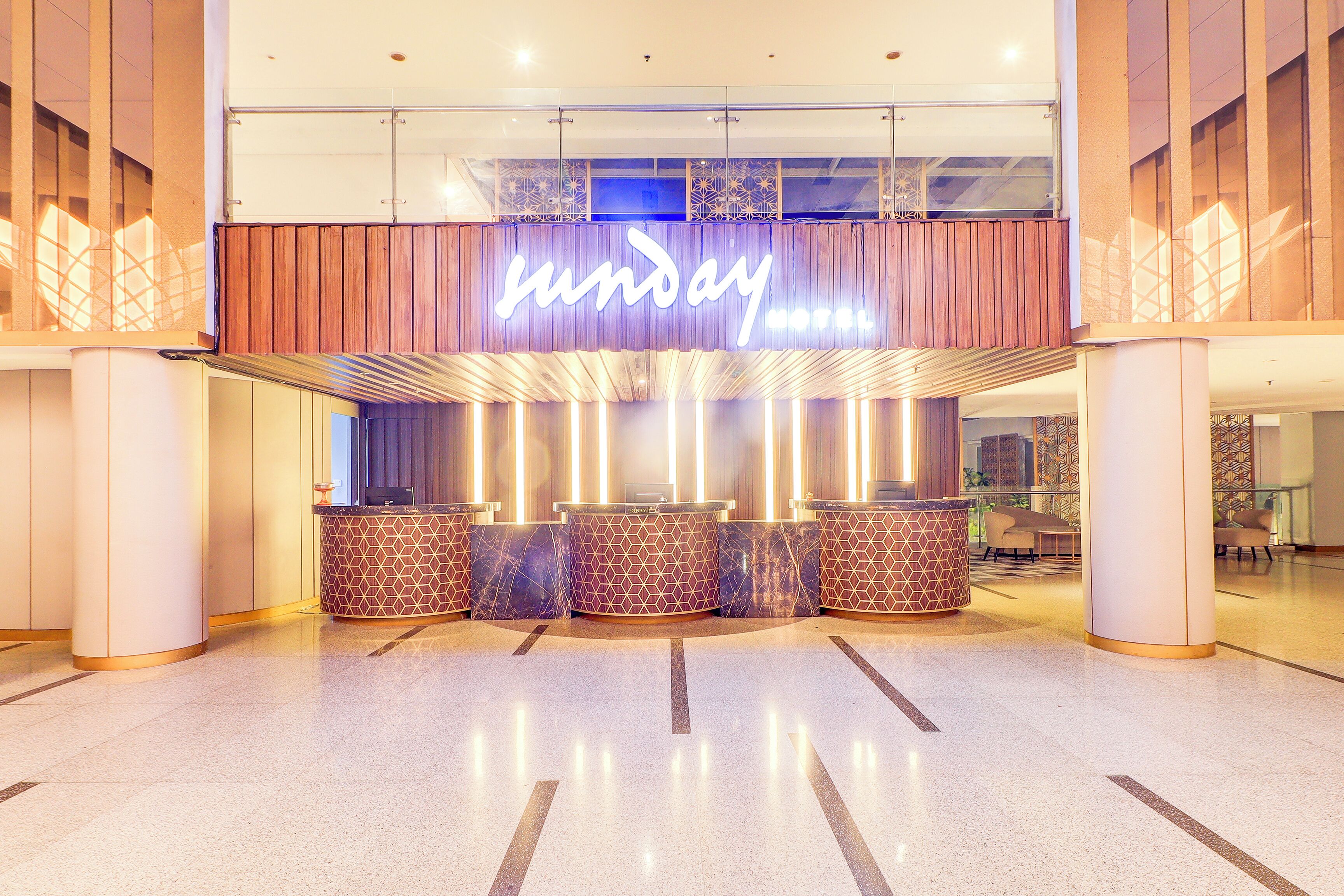 A hotel reception area with a prominent 'Sunday' sign, multiple reception counters, and a modern interior design.