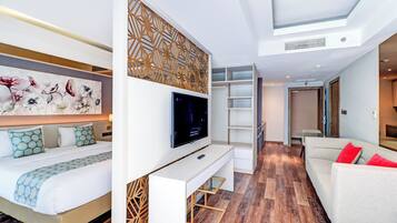 A modern hotel room with a bed, a TV, a desk, and a sofa.