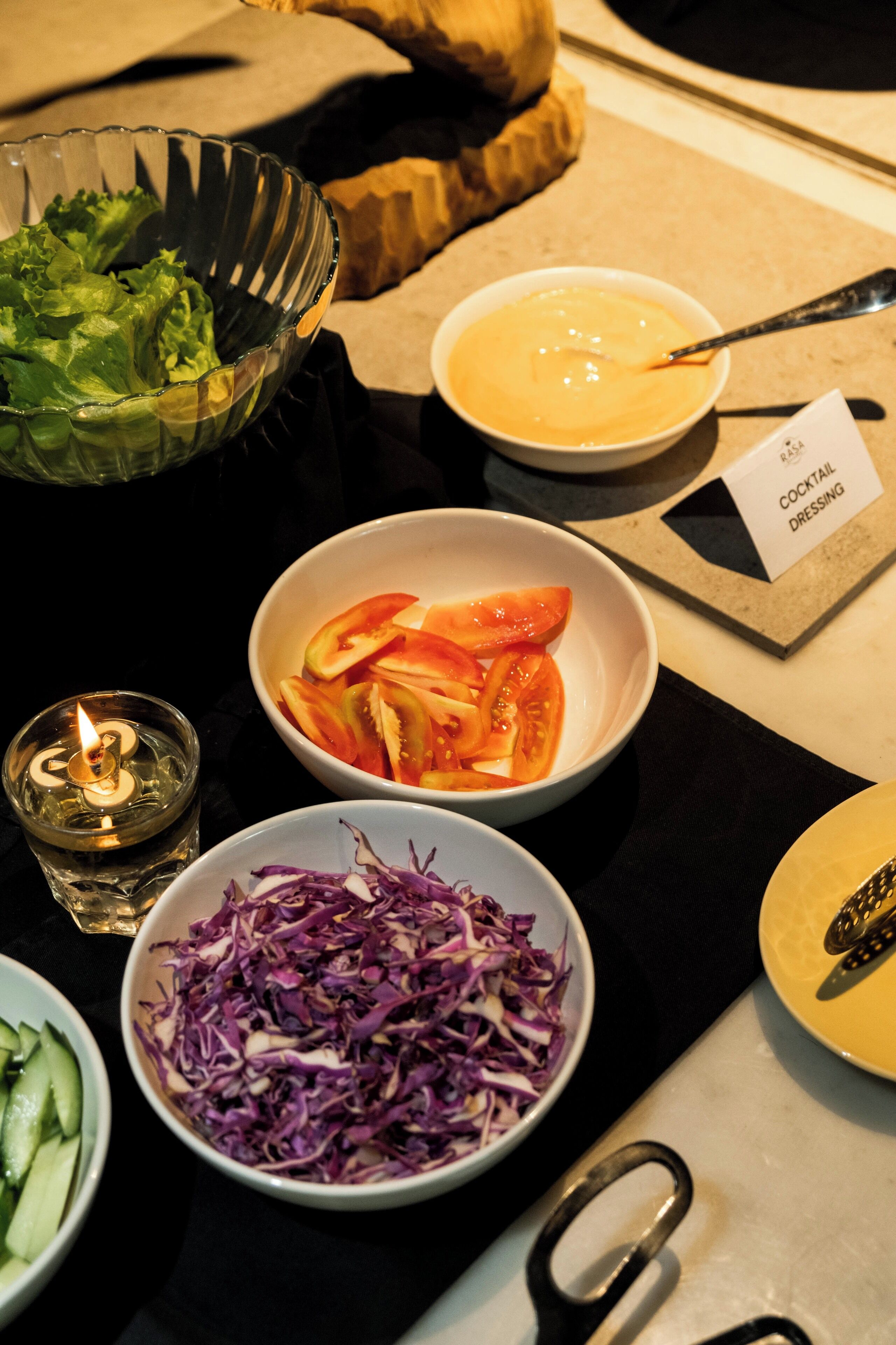 Ein Tisch mit verschiedenen Speisen, darunter ein Salat, Tomatenscheiben und eine Schüssel Krautsalat.