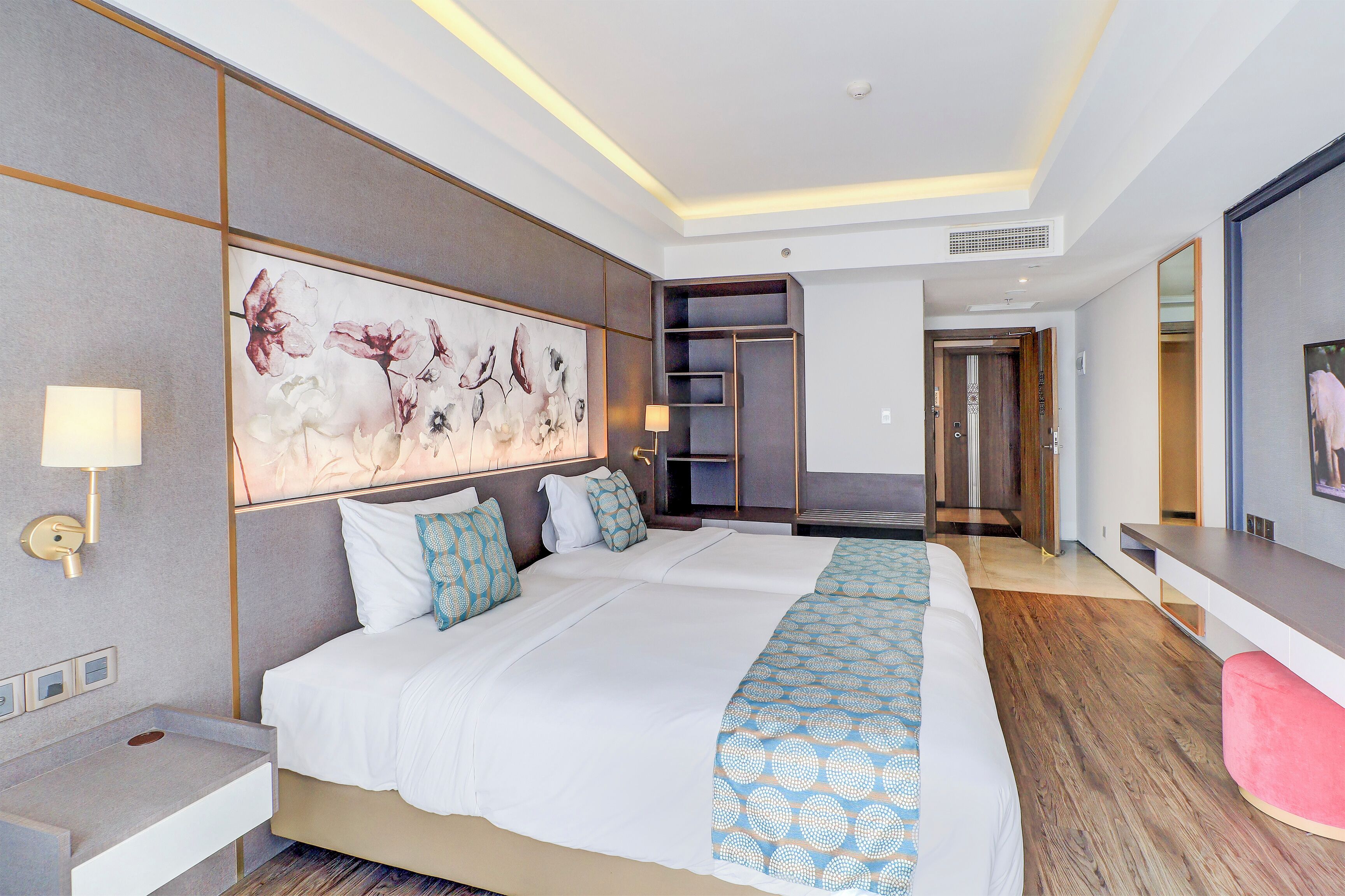A hotel room with a large bed, bedside tables, a wall-mounted artwork, and a modern design.